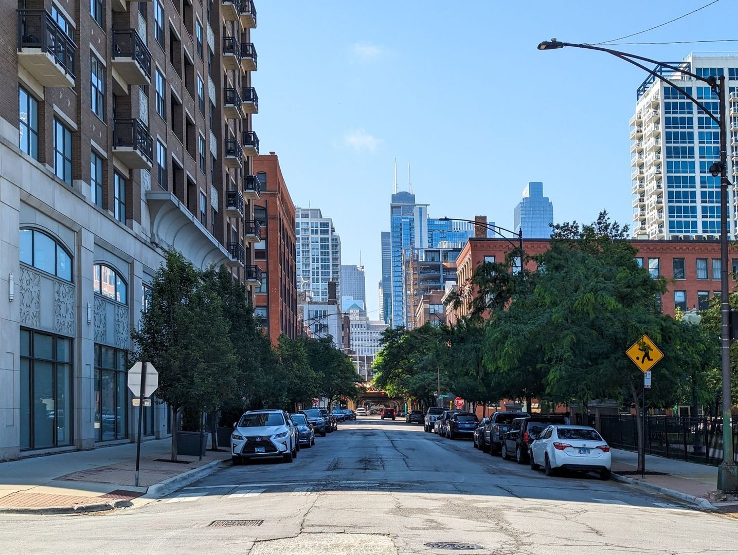 Urban street with apartments, offices, trees, parked cars, and a skyline